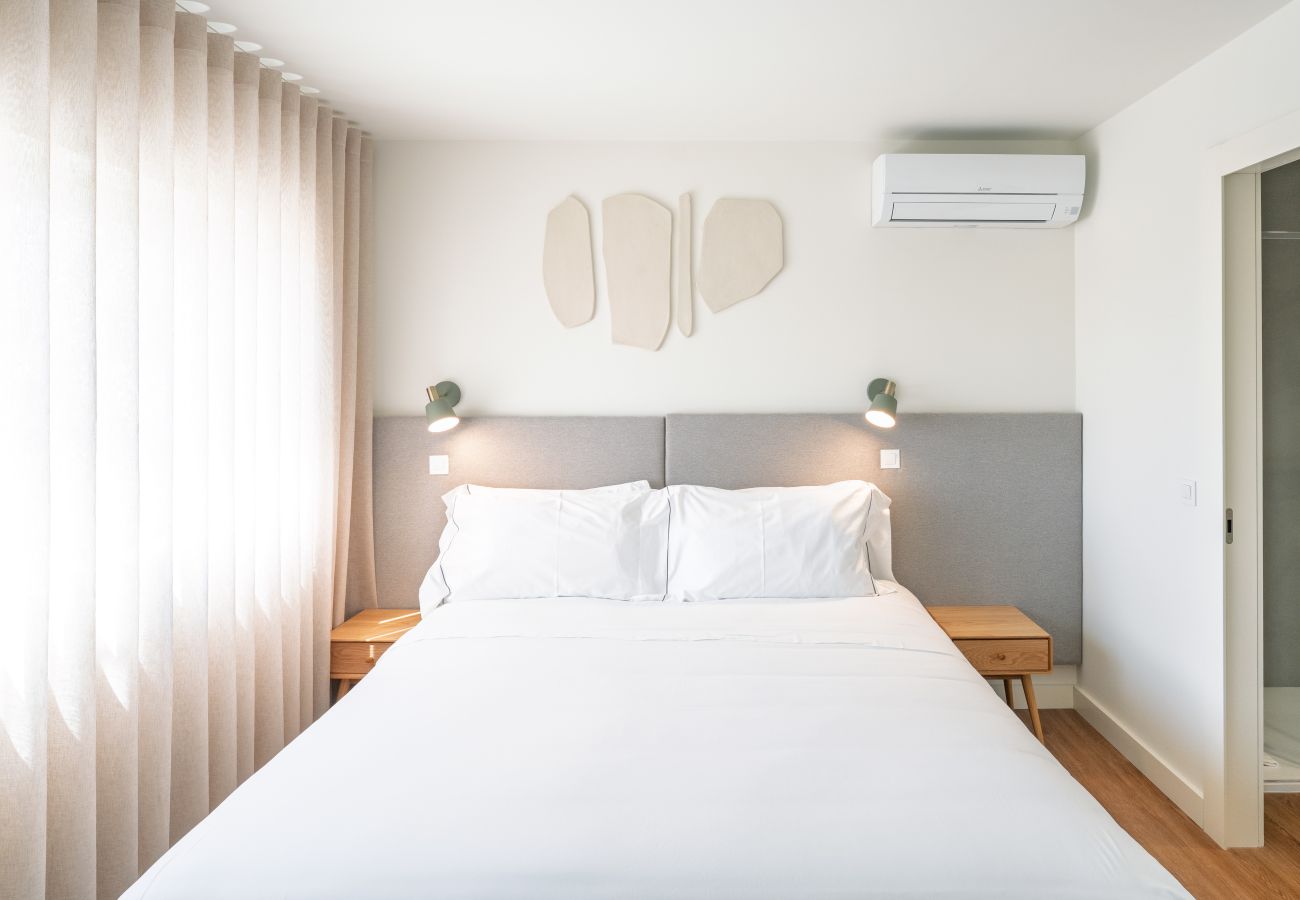 Quarto moderno com cama, roupeiro e luz natural