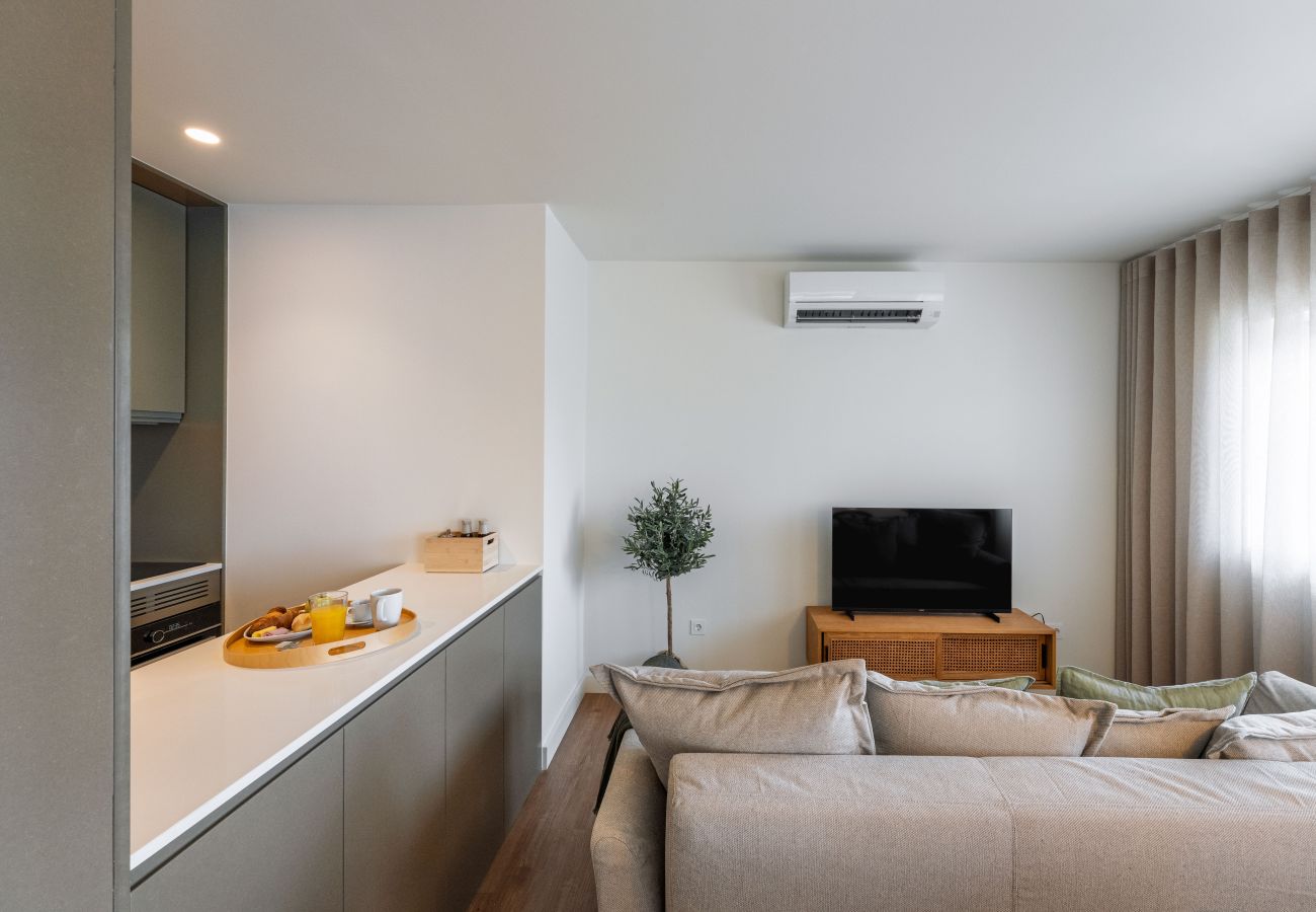 Salon moderne avec canapé, télévision connectée et accès à la terrasse
