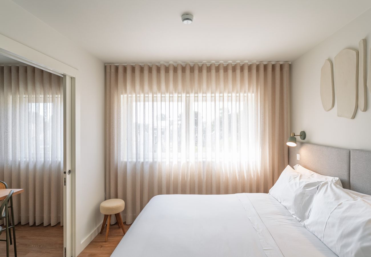 Chambre avec lit double, grandes fenêtres et vue sur la ville, idéale pour les séjours d'affaires.